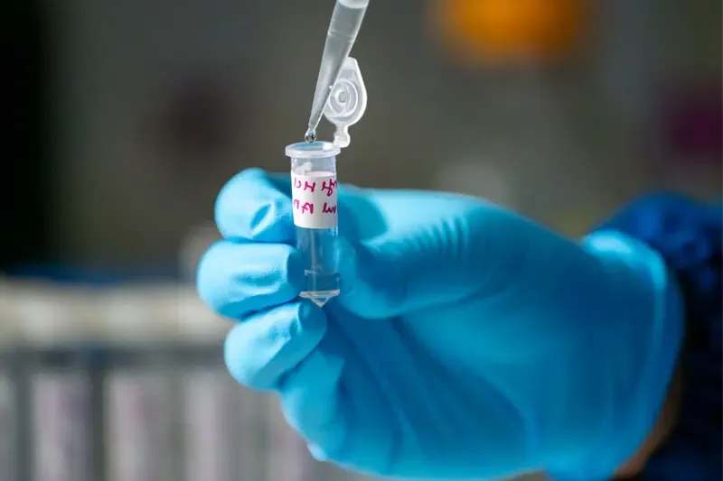 A gloved hand holding a sample of fentanyl in a test tube.